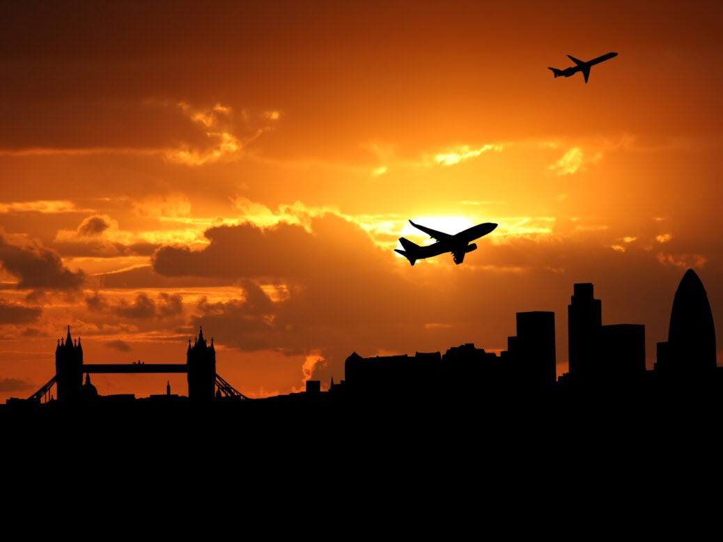 Plane flying over London, UK at sunset.